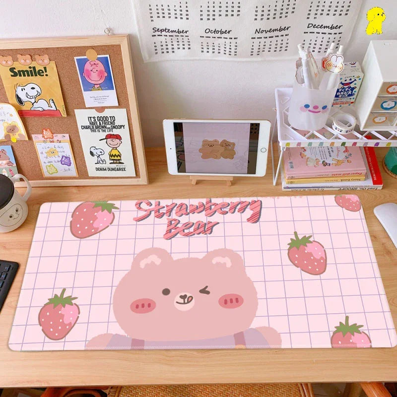 Cute desk setup with Strawberry Bear pink desk mat, cartoon stationery, and tablet display.