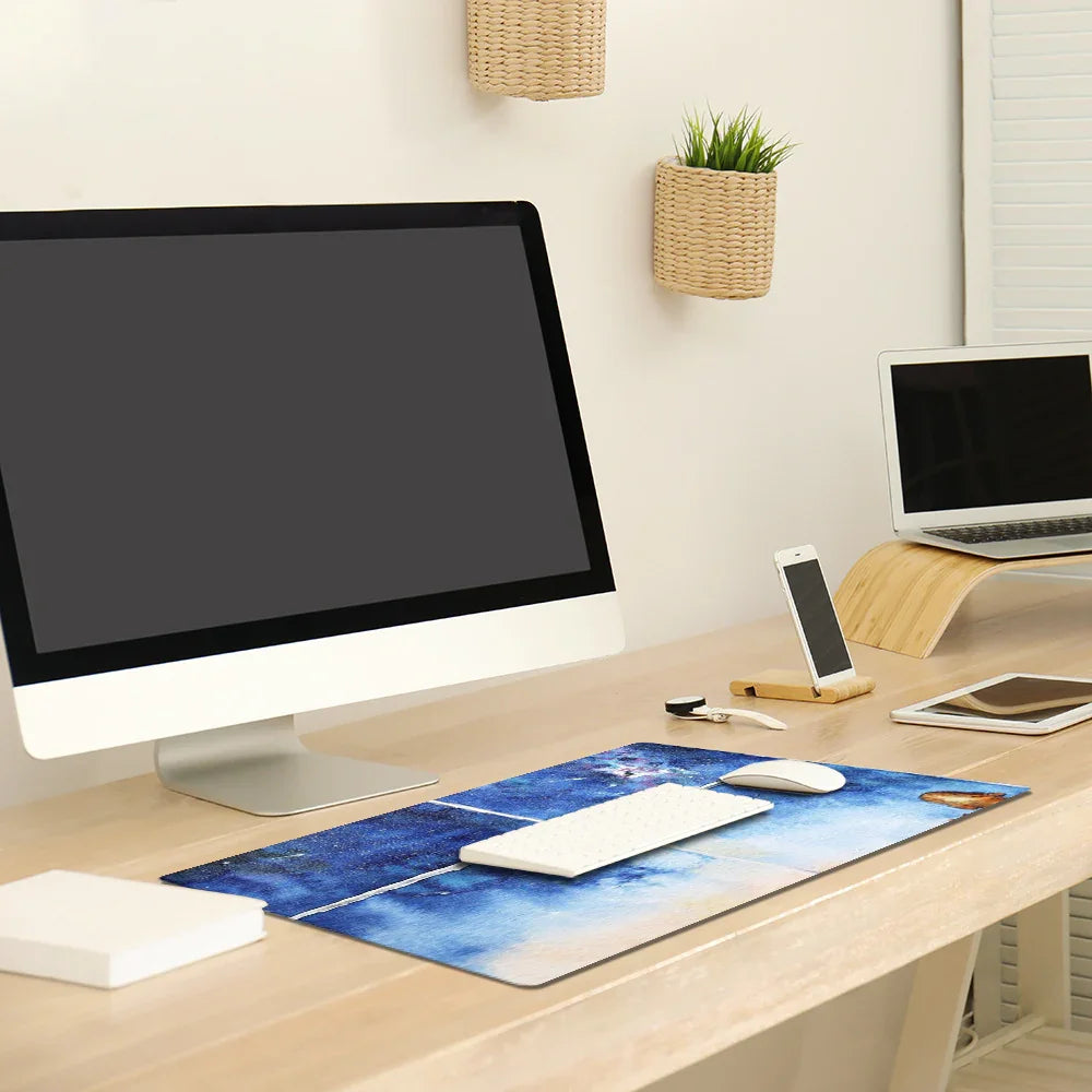 Modern workspace with computer, keyboard, blue desk mat, phone, and ergonomic laptop stand.