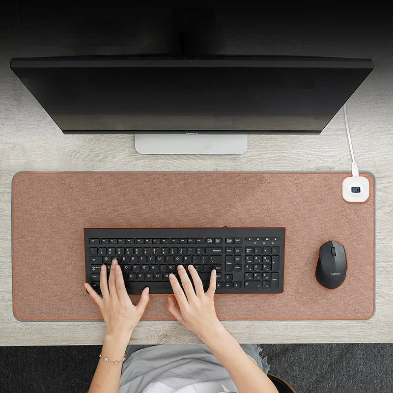 Overhead view of ergonomic desk setup with brown desk mat, monitor, keyboard, and mouse.